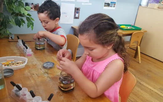 a couple of children sitting at a table with food and drinks