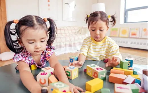 a couple of young girls playing with blocks