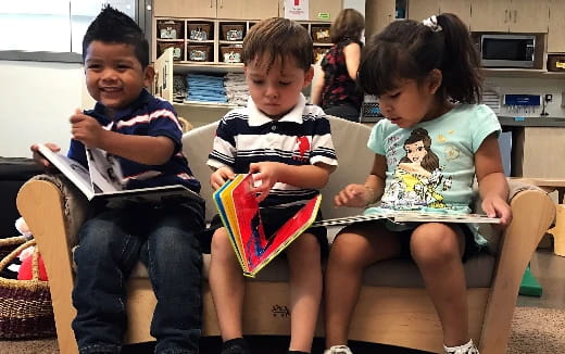 a group of children sitting on a bench reading books