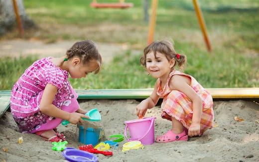 a couple of young girls playing in the sand