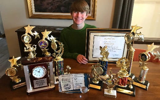 a person standing behind a table full of antique clocks