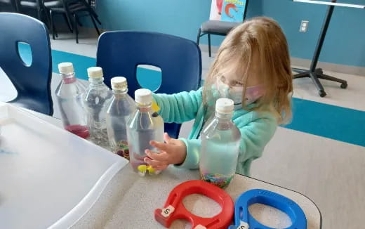 a child sitting at a table with bottles of water