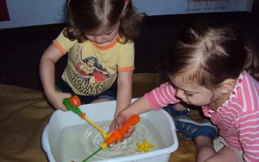 a couple of young girls playing with a toy