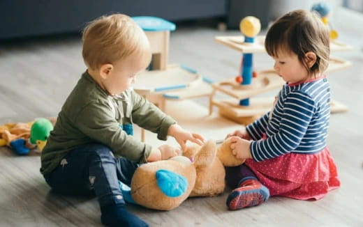 a couple of children playing with a stuffed animal