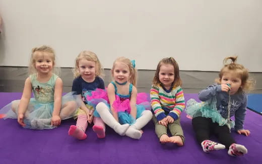 a group of children sitting on a purple mat