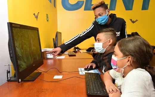 a group of people wearing masks and looking at a computer screen