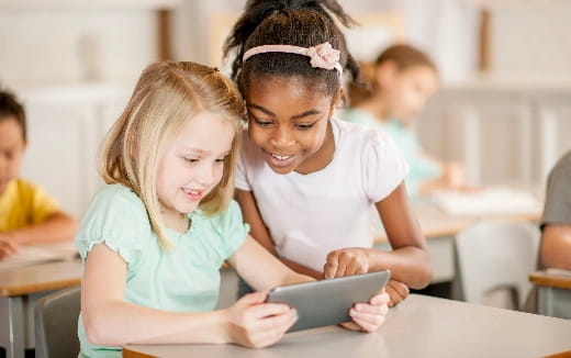 a young girl and a young girl looking at a tablet