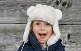 a child wearing a white hat and smiling at the camera