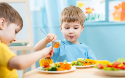 a couple of boys eating at a table