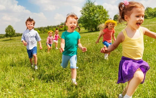 a group of children running in a grassy field