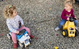 two children sitting on toys