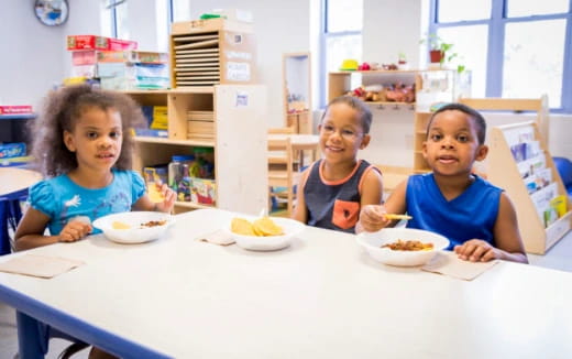 a group of children sitting at a table with food