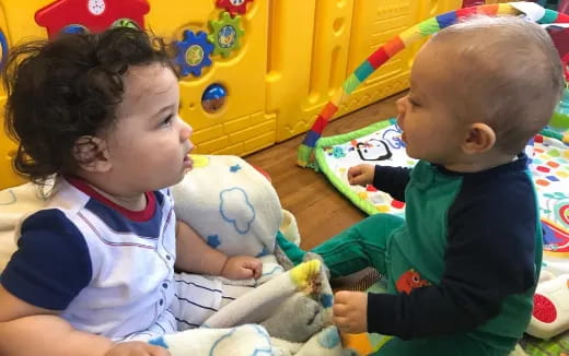 a couple of babies playing with a stuffed animal