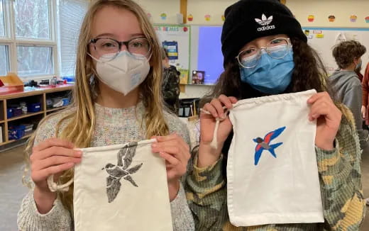 a couple of girls wearing masks and holding a sign