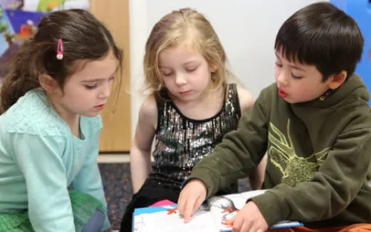 a group of children looking at a book