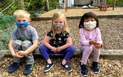 a group of children sitting on a bench with face paint
