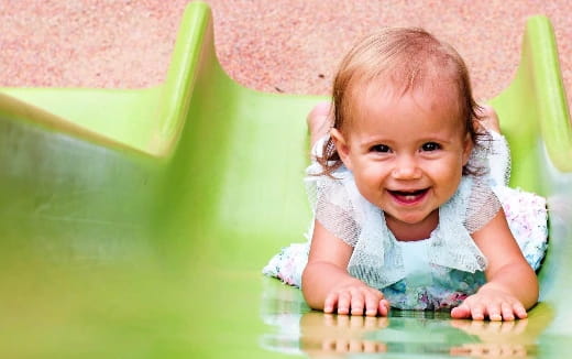 a baby crawling on a green slide