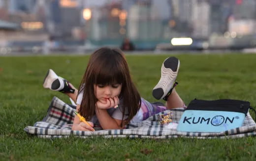 a girl lying on the grass with her hands on her face