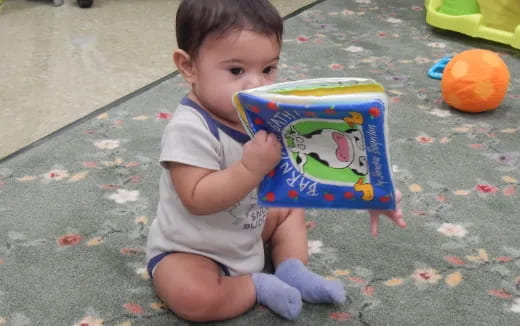 a baby sitting on the ground reading a book