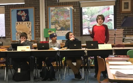 a group of people sitting at a table with laptops