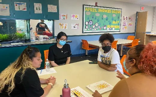 a group of people sitting at a table with masks on