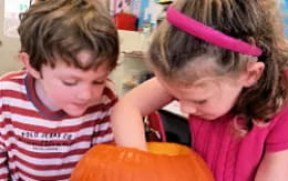 a couple of children looking at a pumpkin
