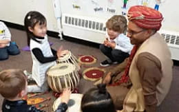 a person and children sitting around a table with a person in a mask