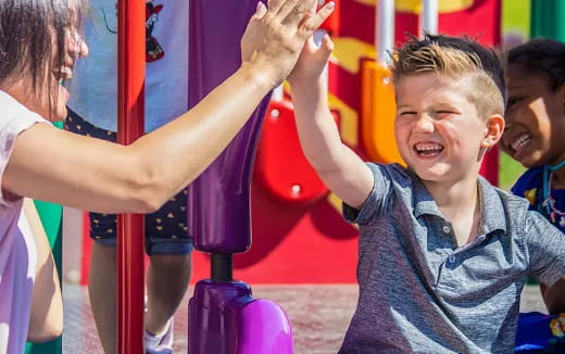 a boy smiling and playing on a playground