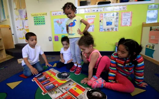 a group of children sitting on the floor in a classroom