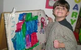 a boy holding a bunch of colorful paper