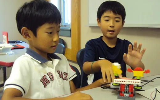 a couple of boys sitting at a table with toys