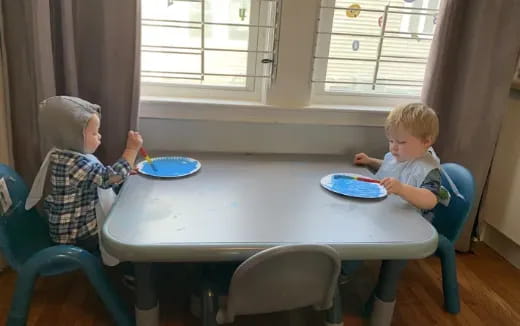 a couple of kids sitting at a table eating