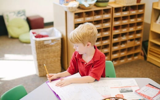 a child sitting at a table writing