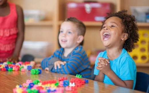 a couple of kids sitting at a table with a cake