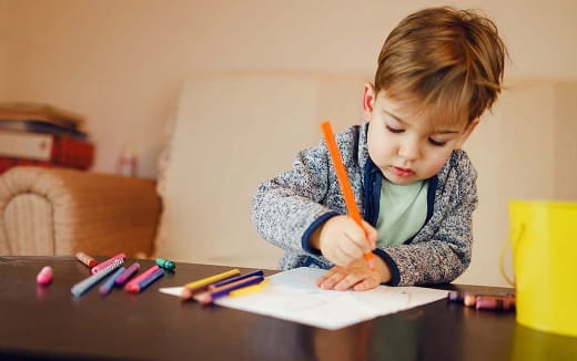 a young boy coloring on a paper