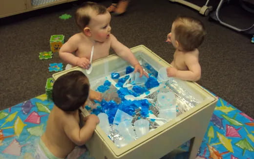a group of babies playing with a cake
