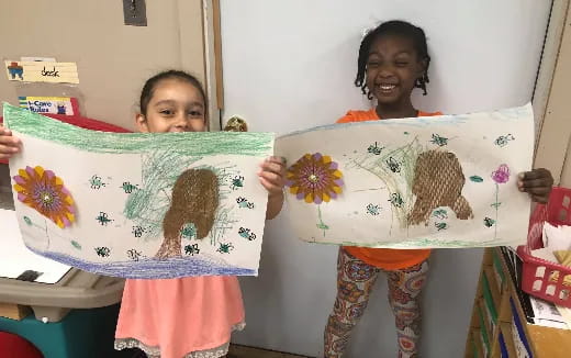a couple of children holding up a drawing
