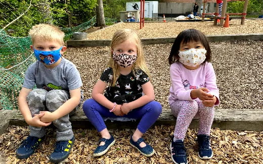a group of children sitting on a bench with face paint
