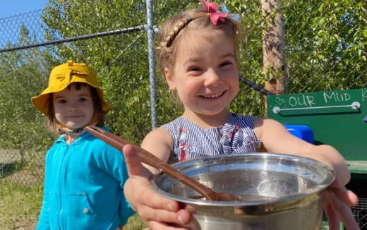 a couple of girls holding a bowl of food