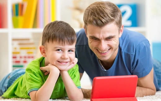 a person and a boy looking at a laptop