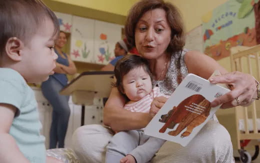 a person reading a book to a young girl