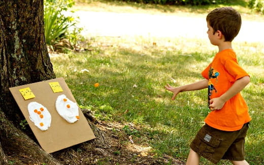 a boy pointing at a box with a face on it