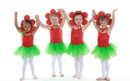 a group of girls in red and green dresses with their arms raised