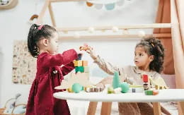 a couple of young girls playing with toys on a table