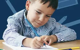 a young boy writing on a piece of paper