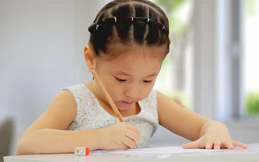 a young girl writing on a book