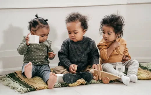 a group of children sitting on the floor looking at a cell phone