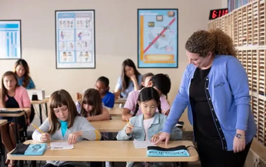 a person standing in front of a classroom with a group of children