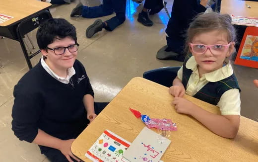 a couple of children sitting at a table with books