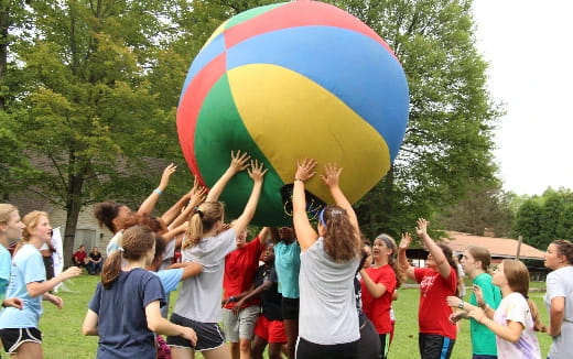 a group of children playing with a large blue and yellow ball